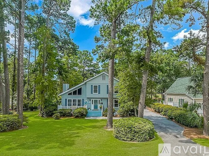 A house surrounded by trees and a green lawn.
