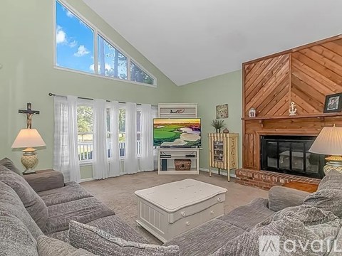A living room with a grey couch and a white ottoman.
