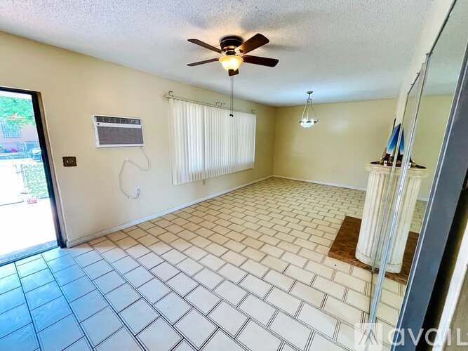 A room with a ceiling fan and tile flooring.
