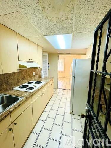A kitchen with a sink, stove and refrigerator.