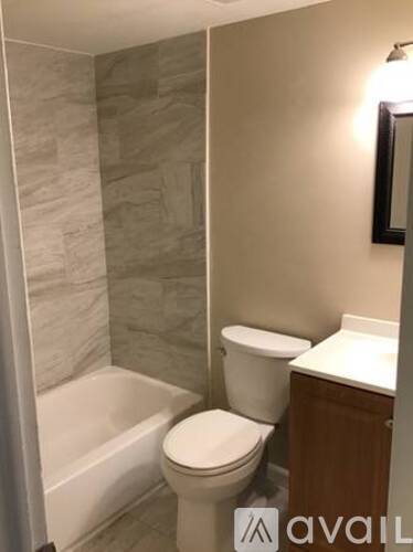 A bathroom with a toilet, a tub, and a cabinet.