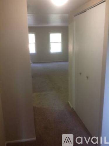 A hallway with a carpeted floor and a door on the right.