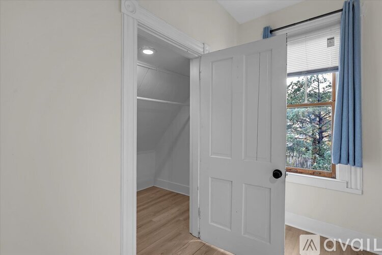 A white door is open to a room with a window.