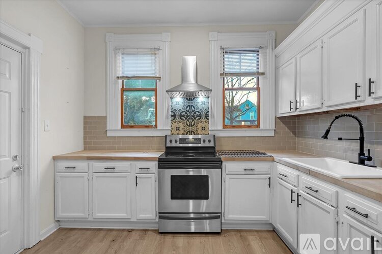 A kitchen with white cabinets and a stove top oven.