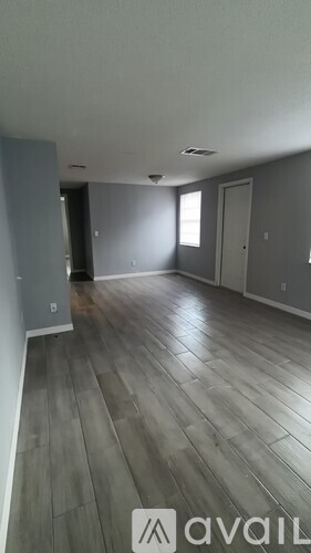 A room with wooden flooring and a wall on the left side.