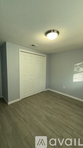 A room with a white door and wooden flooring.