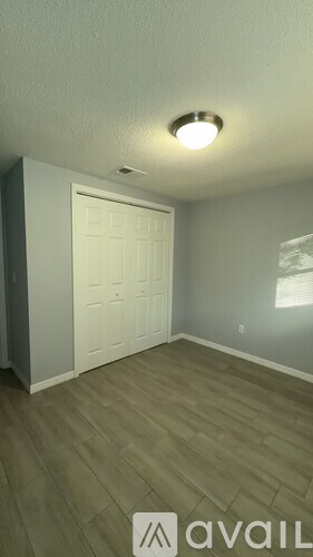 A room with a white door and wooden flooring.