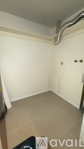 A room with a white wall and a pipe on the ceiling.