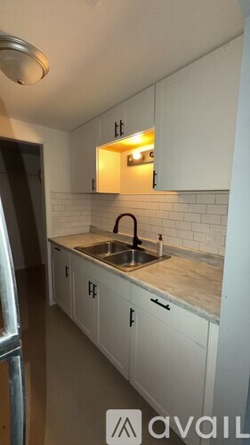 A kitchen with white cabinets and a sink under a window.