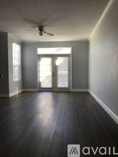 A room with a ceiling fan and sliding glass doors.