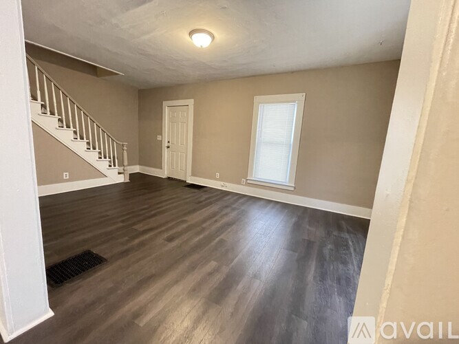 A spacious room with a staircase and a window.