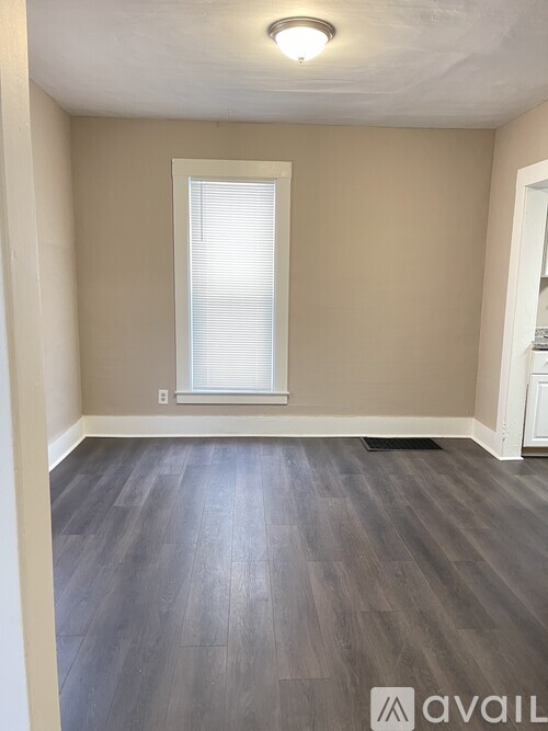 A room with a window and wooden flooring.