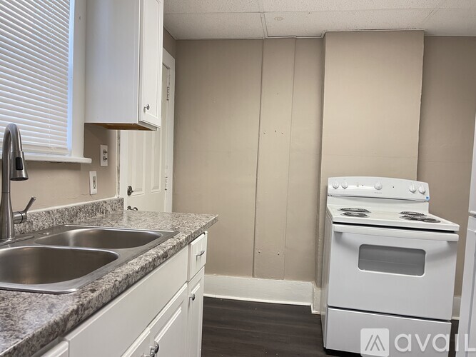 A kitchen with a white stove and sink.