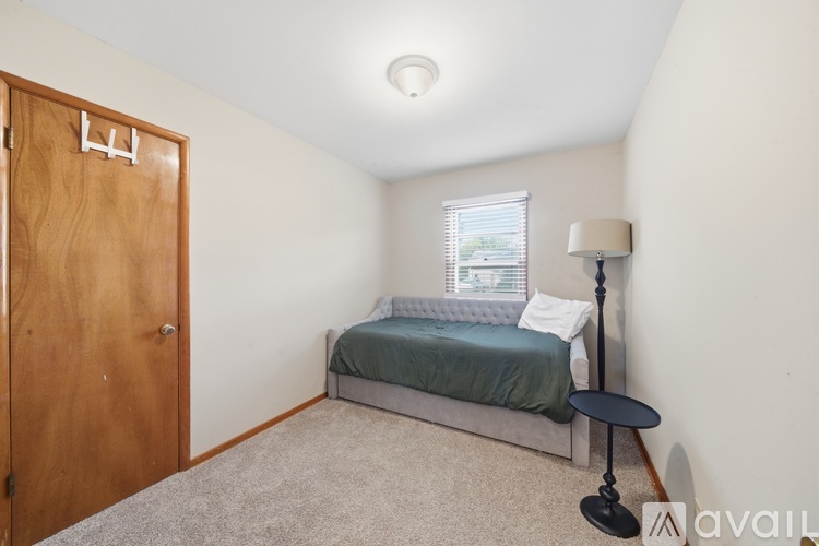 A bedroom with a bed, lamp, and carpeted floor.