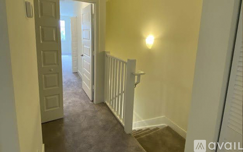 A hallway with a light on the wall and a door at the end.