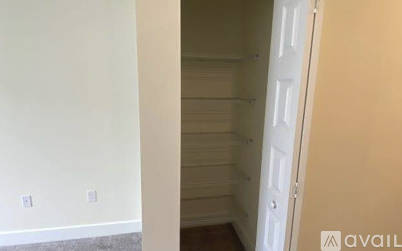 A white door is in a room with a white wall and a wooden floor.