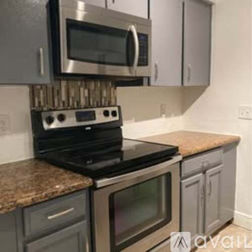 A kitchen with a black stove top oven and a microwave above it.