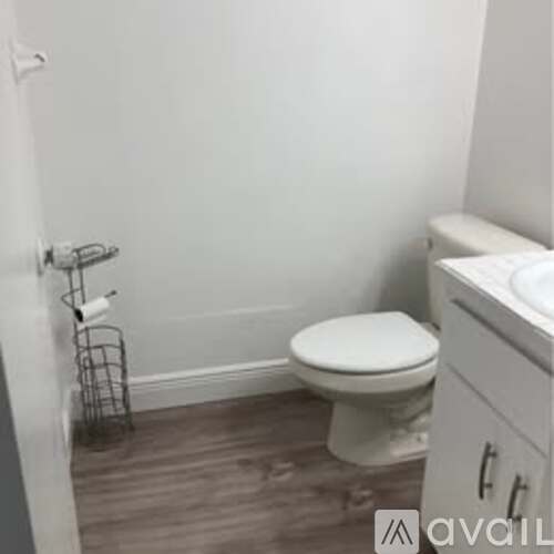 A white toilet in a small bathroom with a white cabinet.
