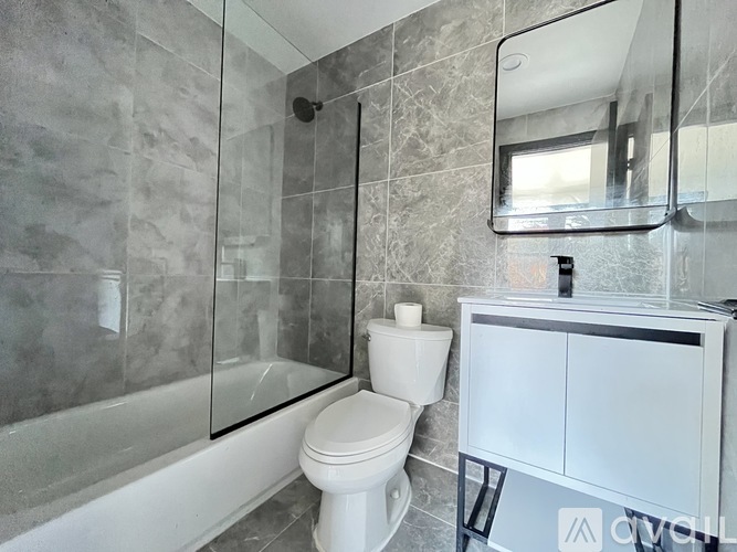 A white toilet sits next to a glass shower stall in a bathroom.