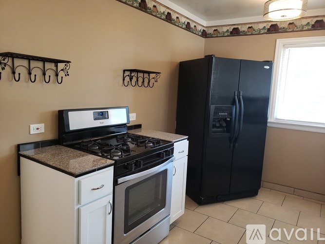A kitchen with a black fridge, white oven and a black stove top.