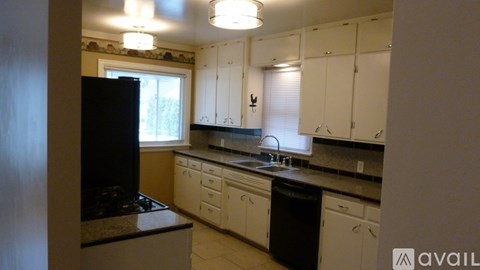 A kitchen with white cabinets and a black refrigerator.