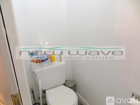 A white toilet in a small bathroom with a sign that says "nuwave real estate".