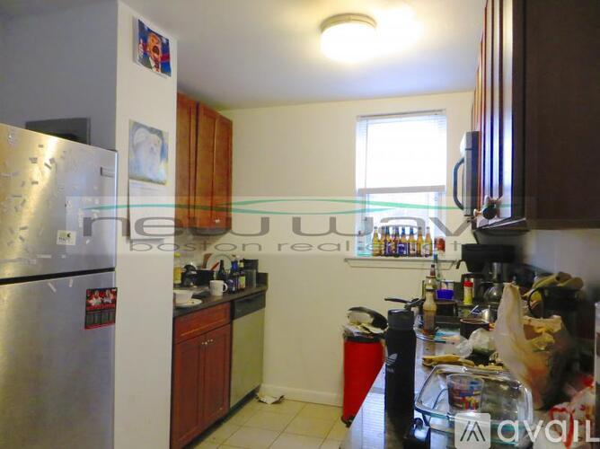 A kitchen with a refrigerator, cabinets, and a counter with various items on it.