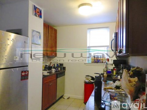 A kitchen with a refrigerator, cabinets, and a counter with various items on it.