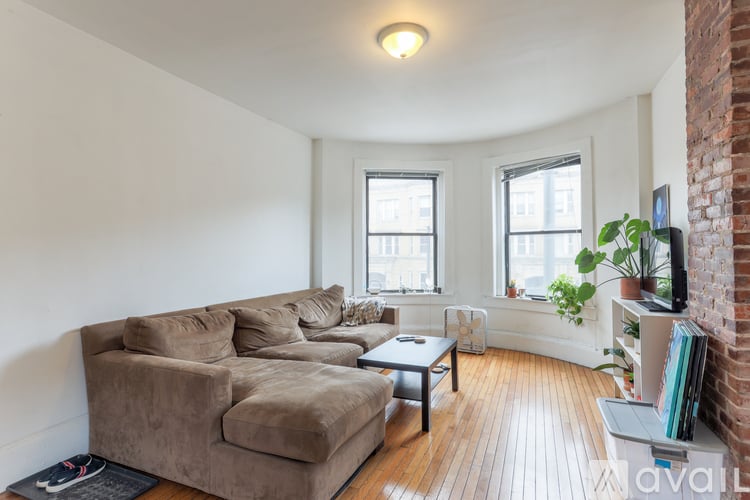 A living room with a brown couch and a brick wall.