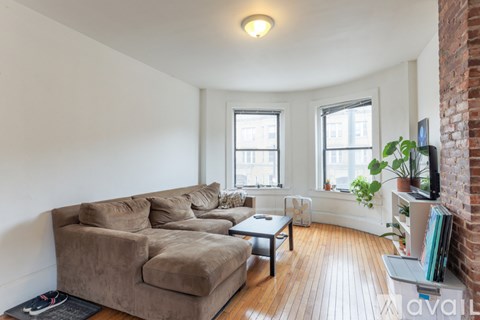 A living room with a brown couch and a brick wall.