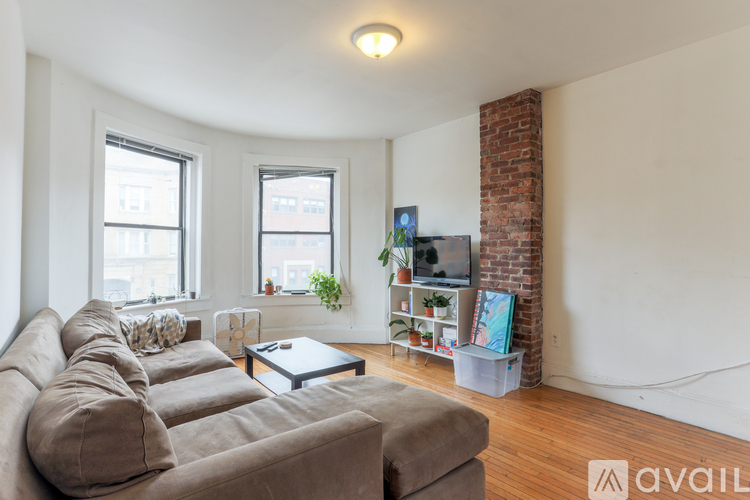 A living room with a couch, a coffee table, and a brick fireplace.