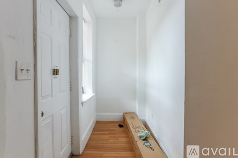 A long hallway with a white door and a bench with a sign on it.