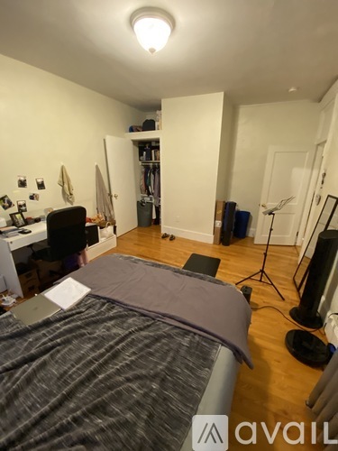 A bedroom with a bed, desk, and a closet.