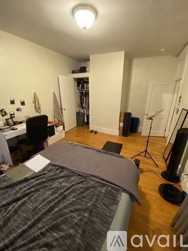 A bedroom with a bed, desk, and a closet.