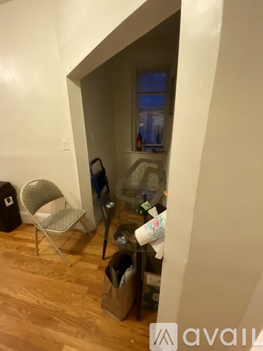 A room with a chair and a table with a bottle on it.