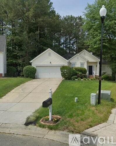 A white house with a grey garage door is situated in a suburban area.