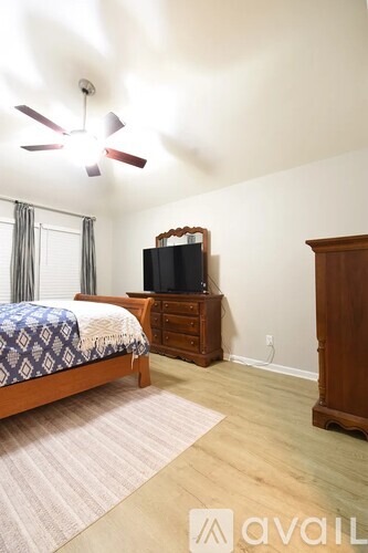 A bedroom with a bed, dresser, and television.
