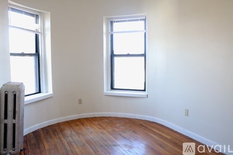 A room with wooden floors and two windows.