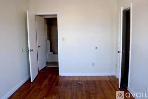 A room with a wooden floor and white walls, with a door on the left and another door on the right.
