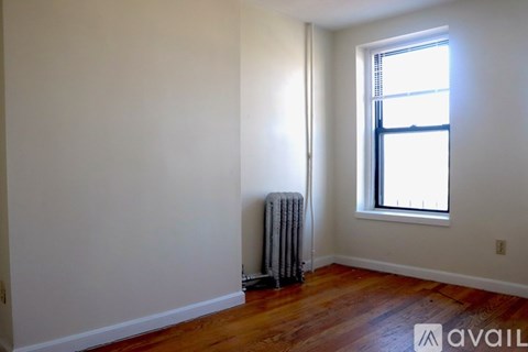 A room with a window and a radiator on the floor.