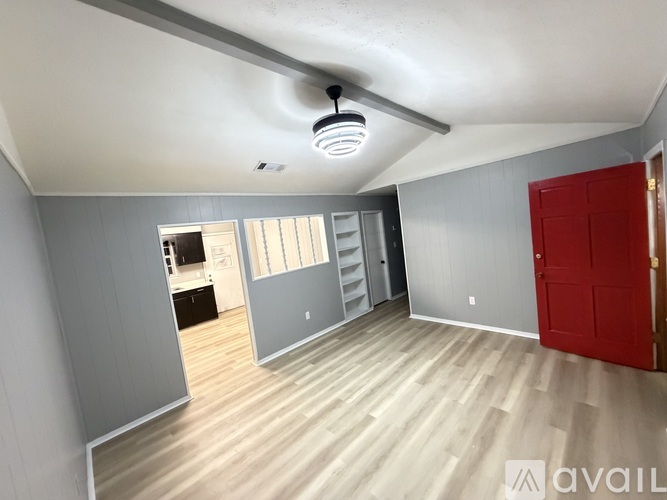 A room with a red door and a wooden floor.