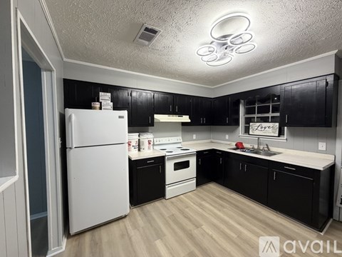 A kitchen with black cabinets and a white fridge.