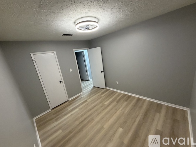 A room with wooden flooring and two doors, one of which is open.