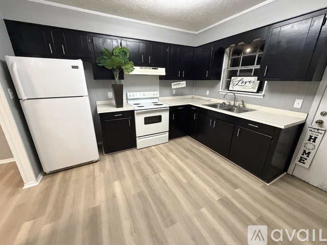 A kitchen with black cabinets and a white fridge.