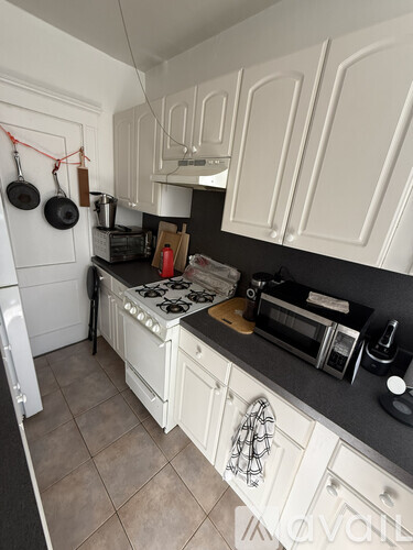 A kitchen with white cabinets and a black countertop.