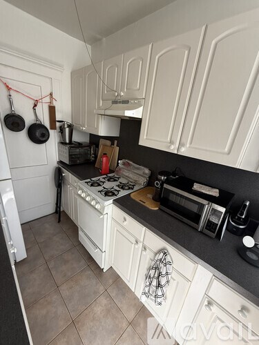 A kitchen with white cabinets and a black countertop.