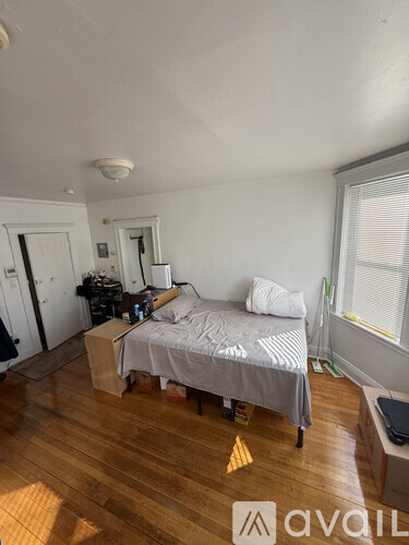 A bedroom with a bed, nightstand, and window.