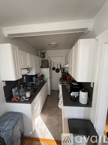 A kitchen with white cabinets and black countertops.