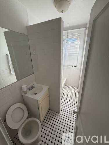 A white toilet with a sink and mirror in a bathroom.