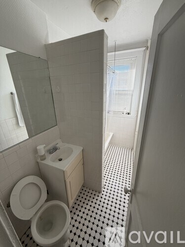 A white toilet with a sink and mirror in a bathroom.